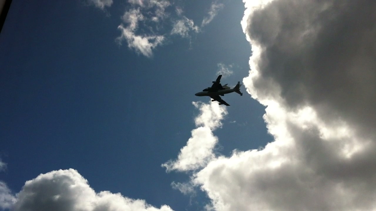 Space Shuttle Enterprise and its carrier aircraft pass close overhead.