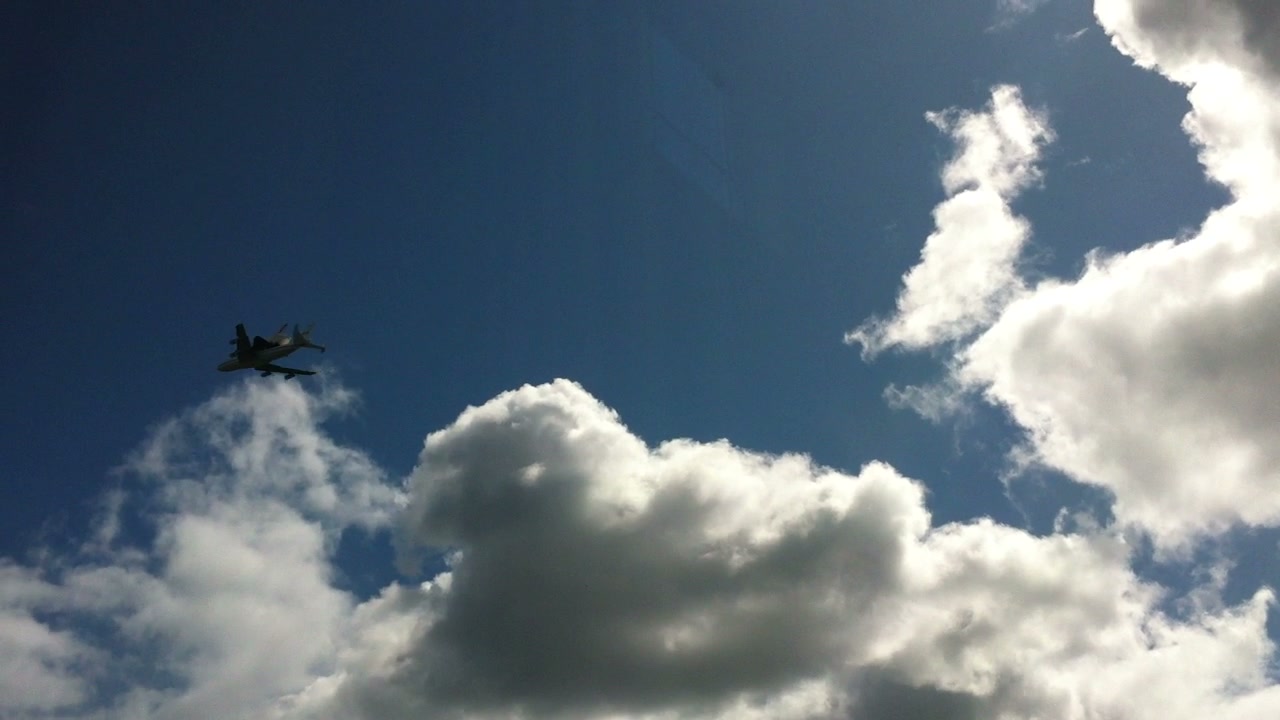 The shuttle carrier recedes into the blue sky beyond the apartment window.