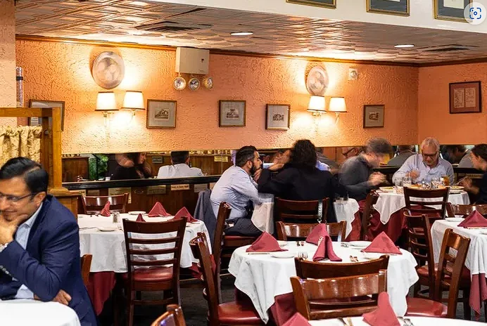 The warmly lit dining room at Pietro’s with white tablecloths, red napkins and guests gathered around the tables