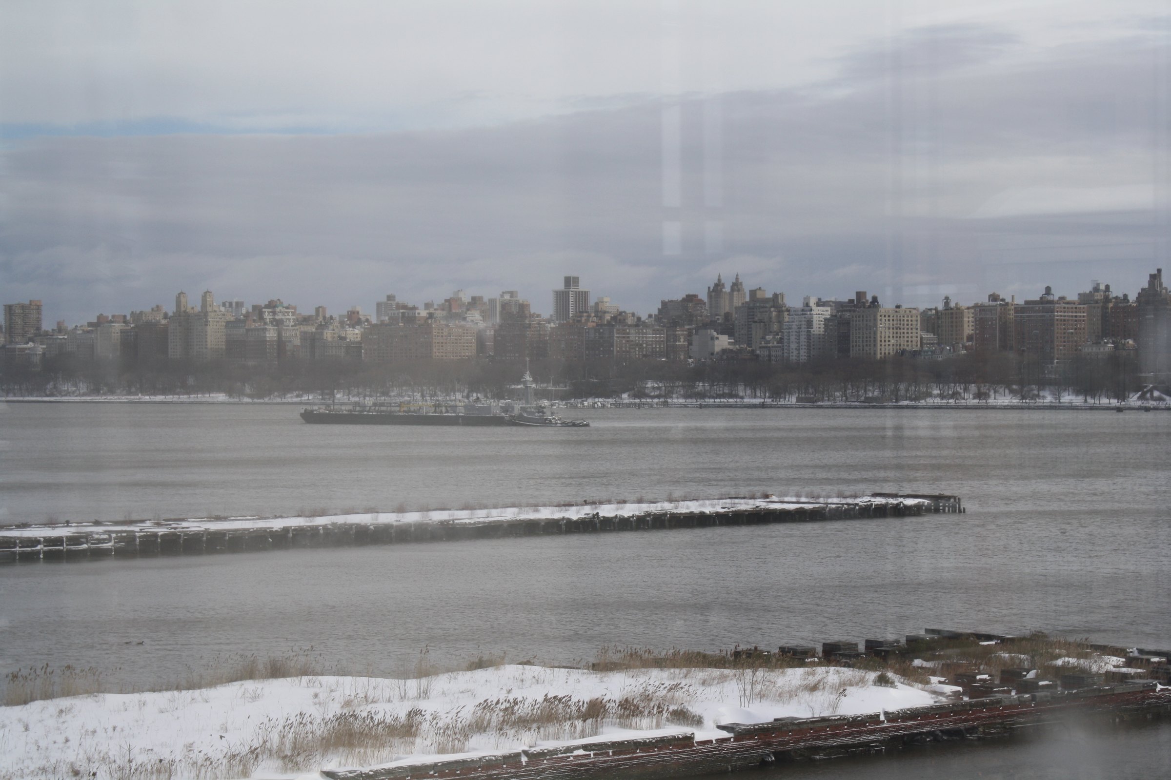 Riverfront and distant city beneath winter cloud.
