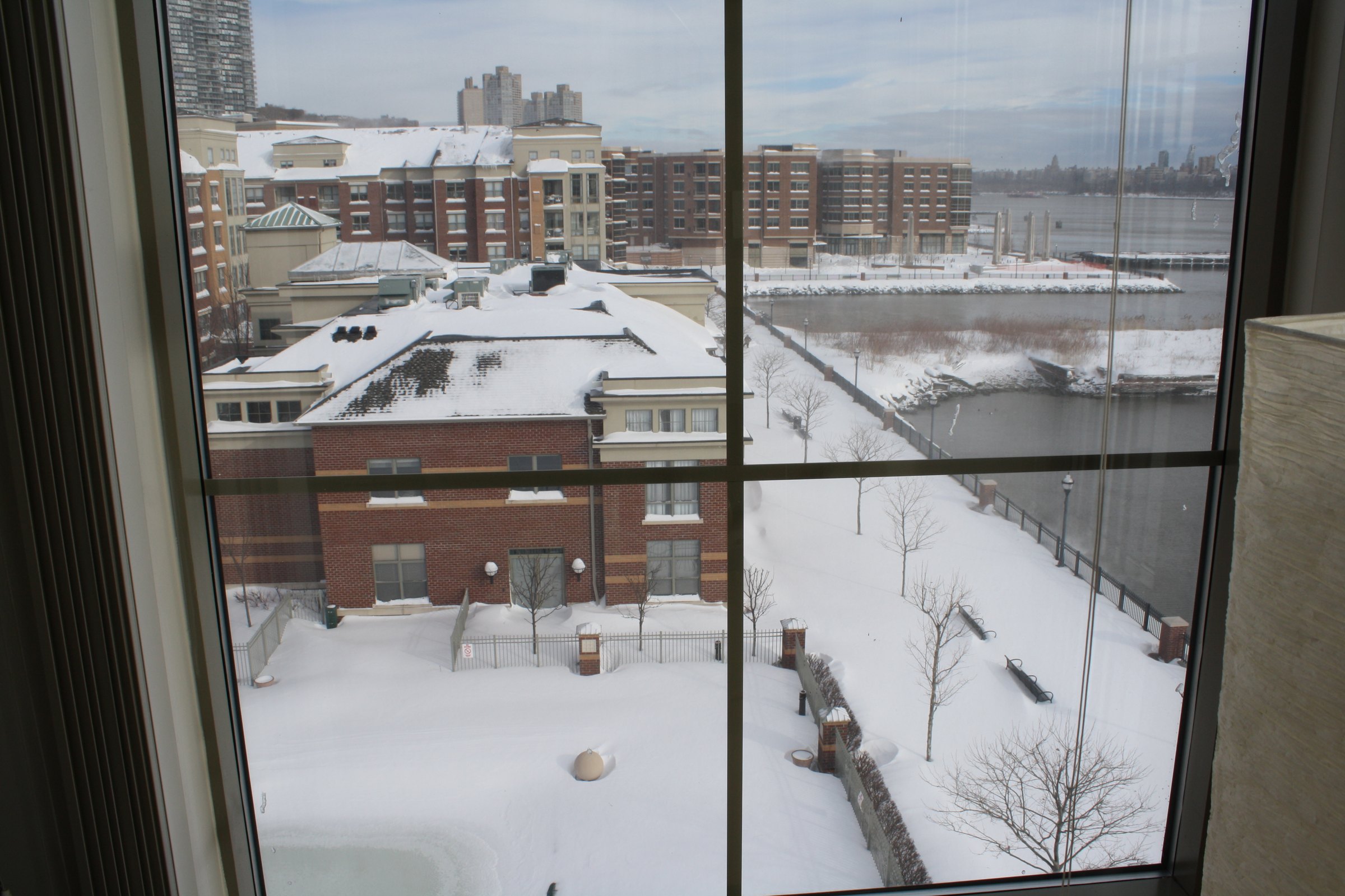 Snowy courtyard and rooftops seen through an apartment window.