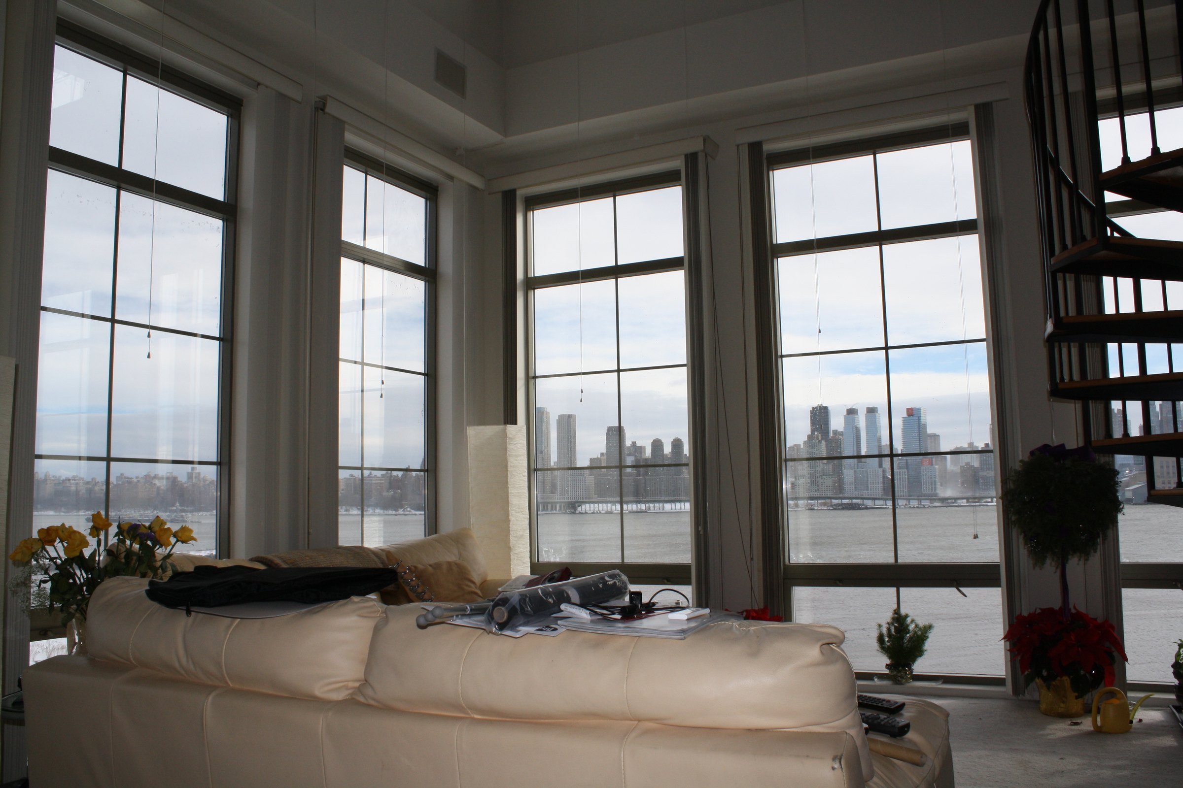 Living room with tall windows overlooking the river and city.