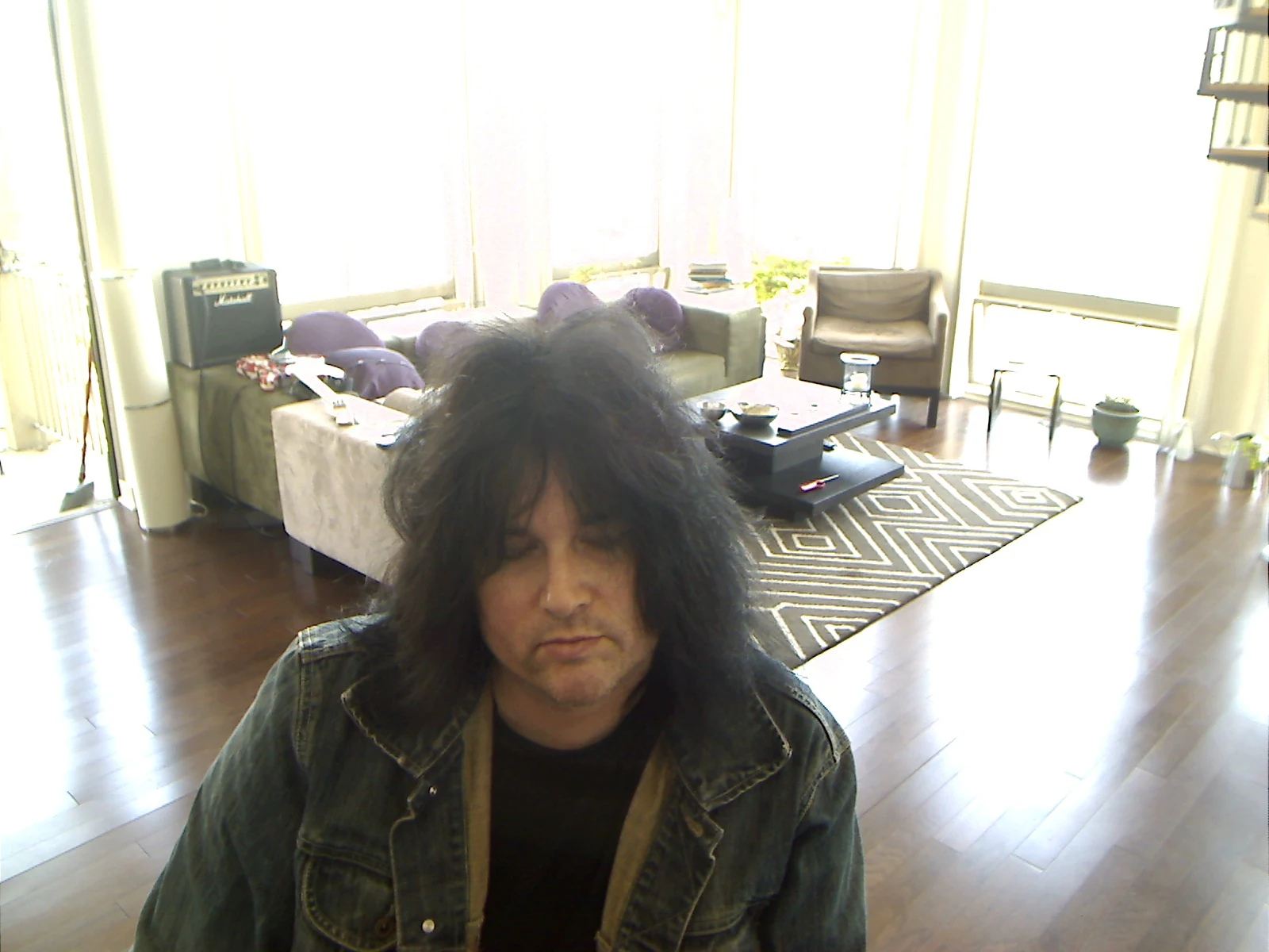 Benny seated in the bright apartment before posing with the guitar.