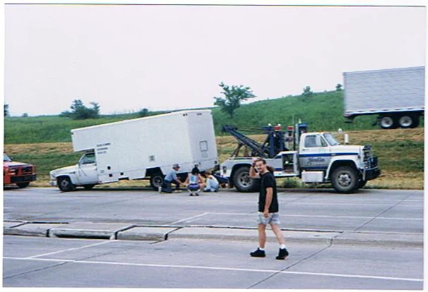 A crew member crosses the road near the disabled equipment truck.