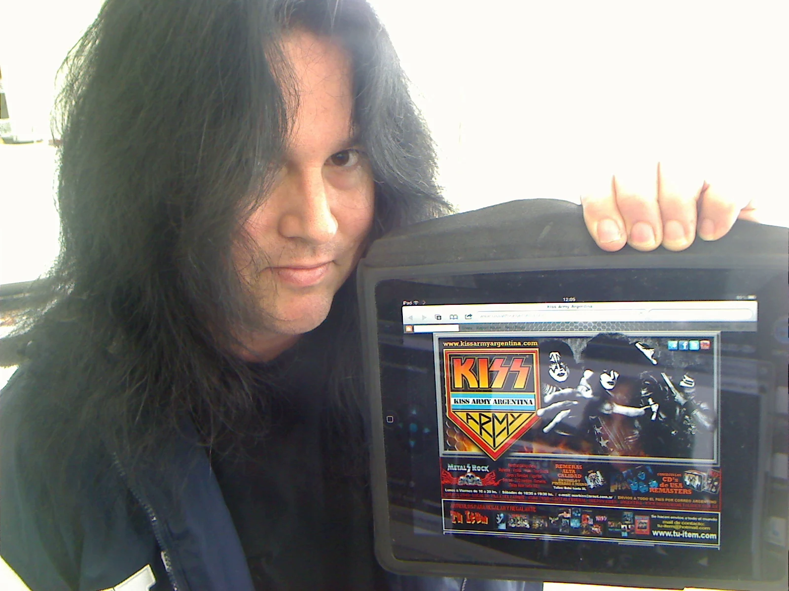 Benny holding an iPad displaying the KISS Army Argentina website.