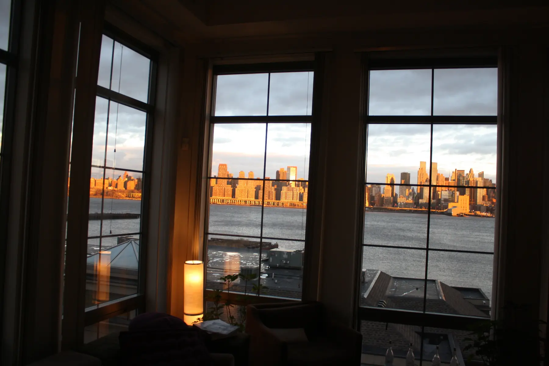 Manhattan framed by the apartment's tall windows in warm evening light.