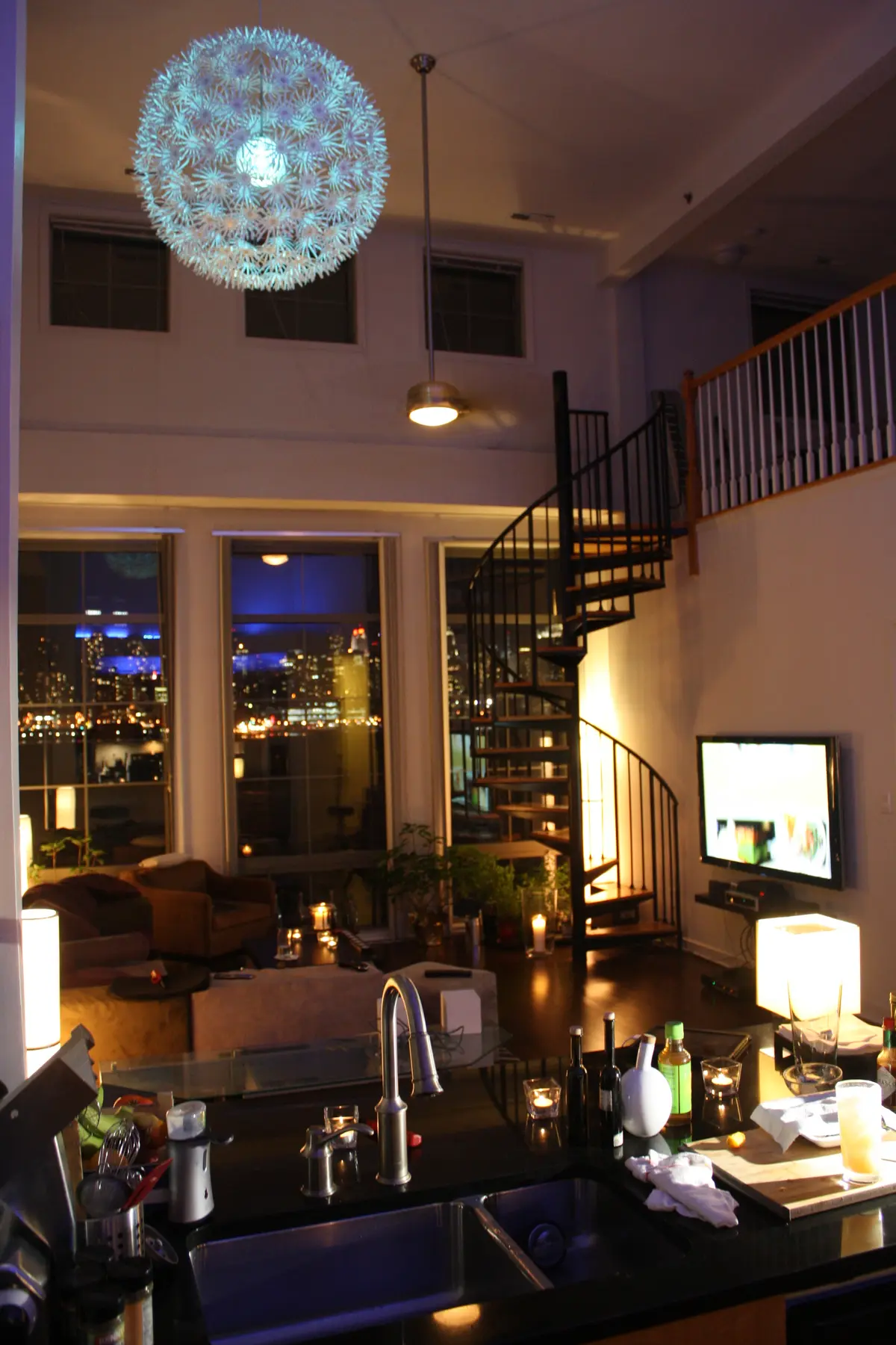 The double-height living space, kitchen and spiral staircase at night.
