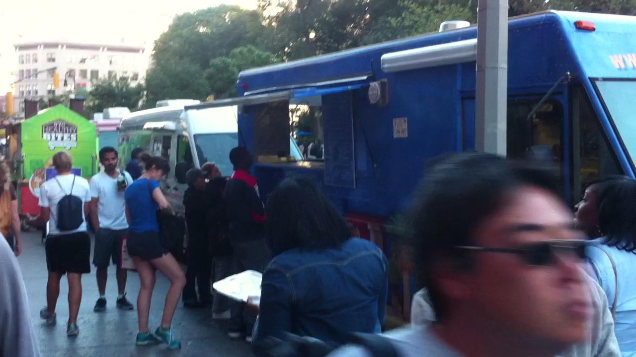 Customers form a line between neighboring food trucks.